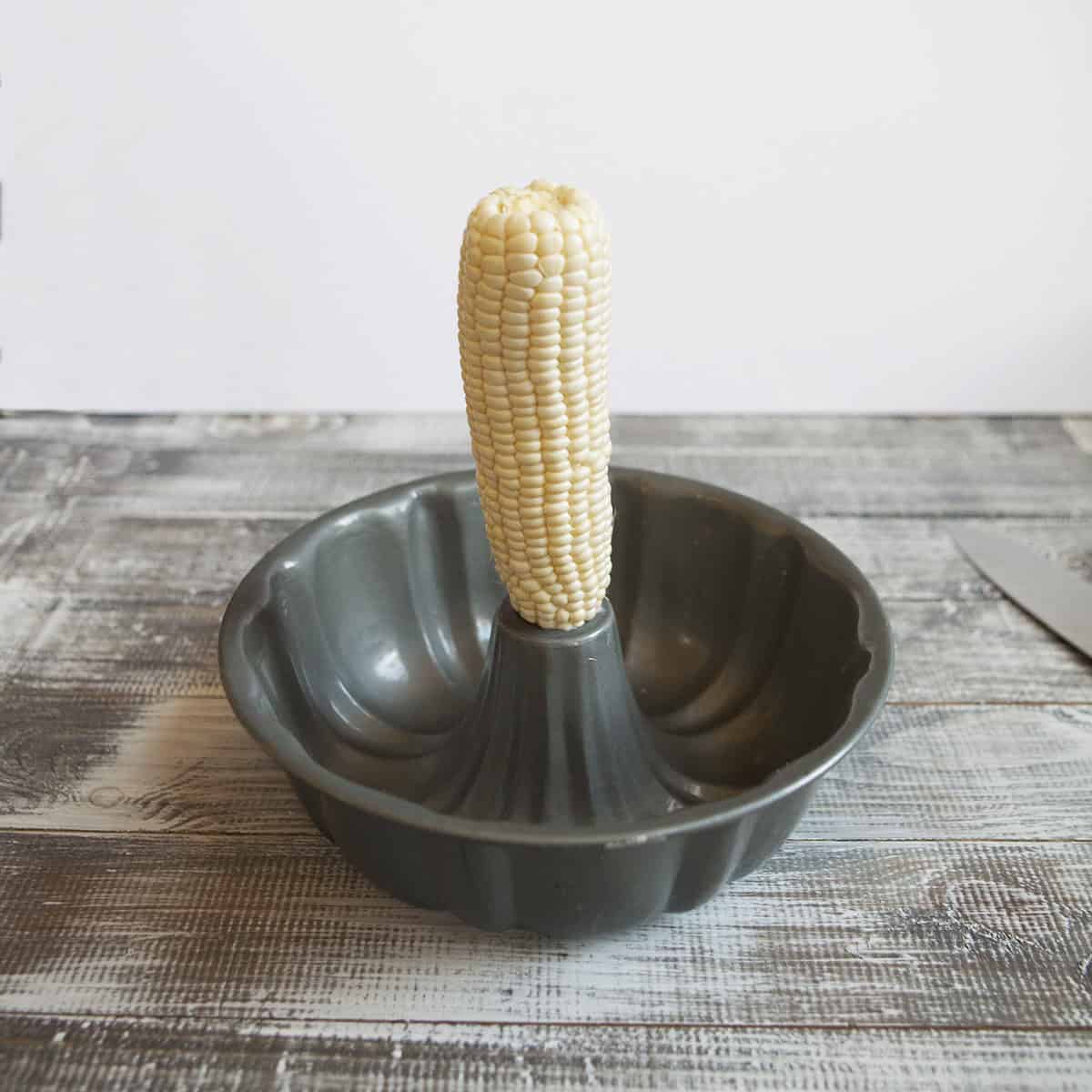 Fresh corn cob standing up in a bundt cake pan.