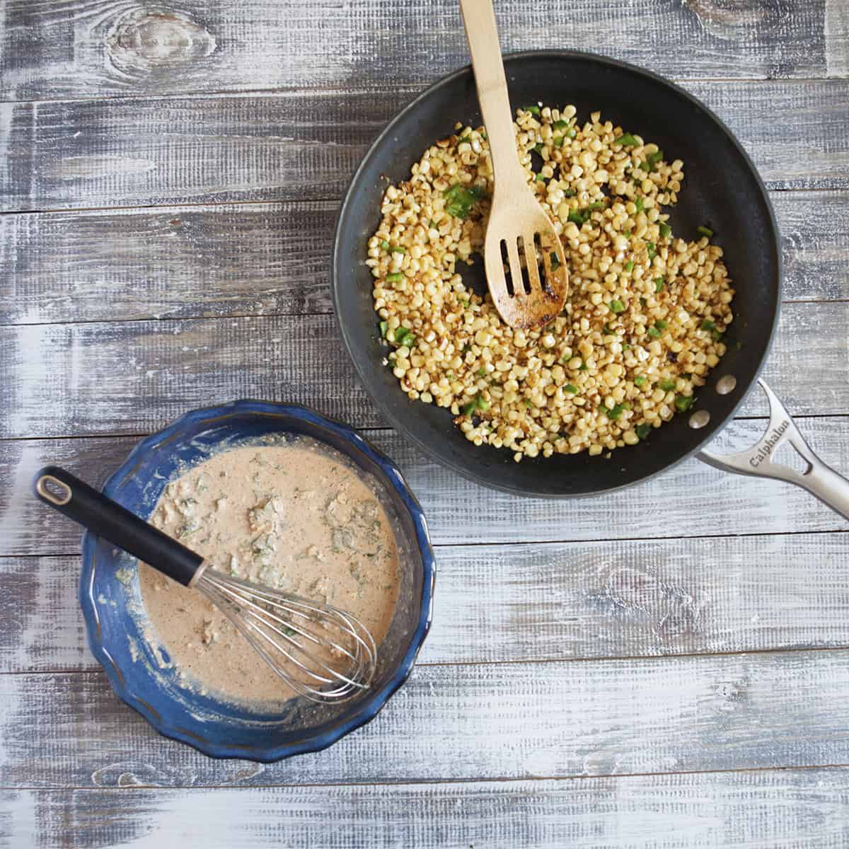 Sauteed corn kernels in a skillet alongside a pie plate filled with creamy ingredients for Mexican street corn in a cup (elote en vaso or esquites).