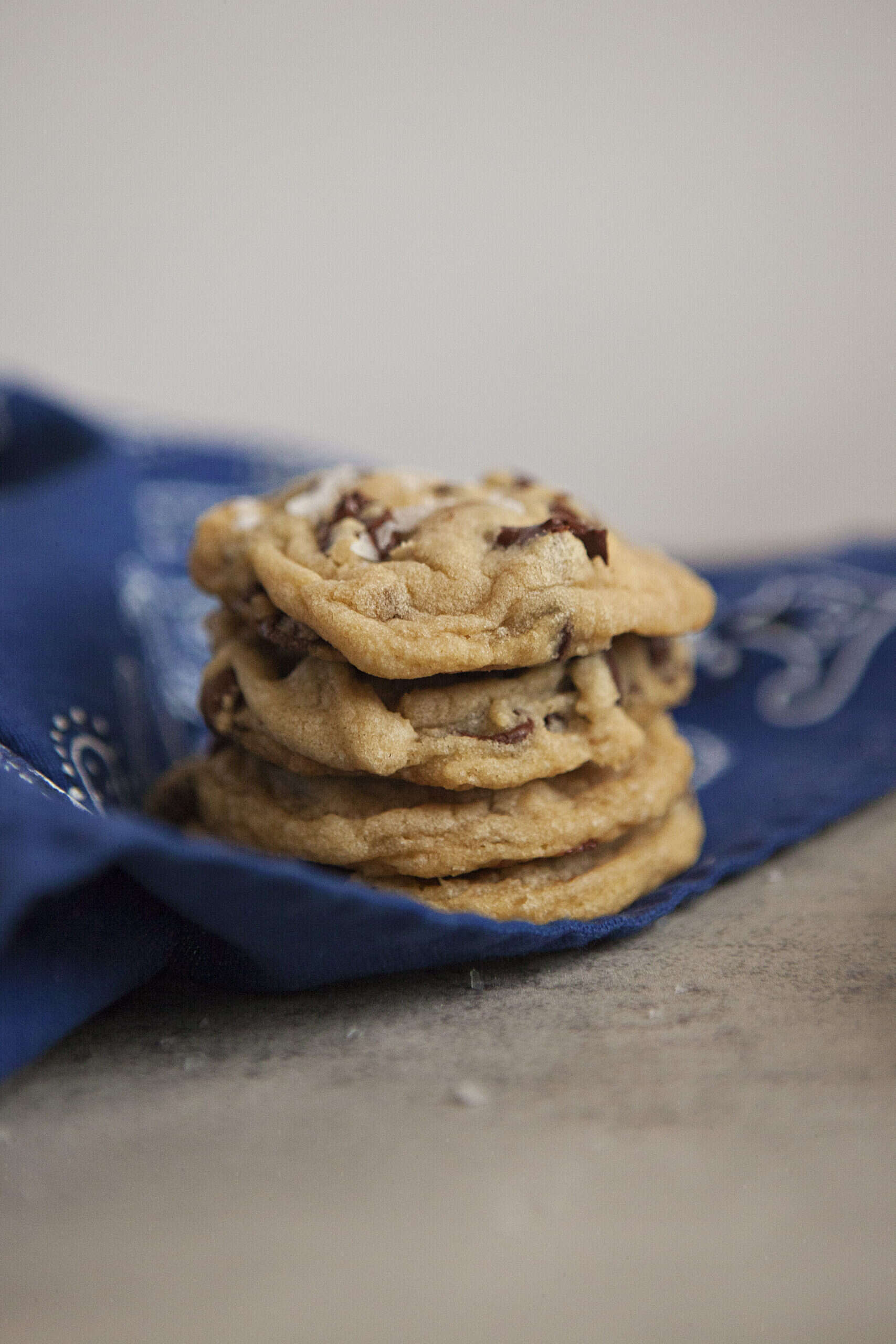 A stack of chocolate chip cookies on a blue kitchen towel.