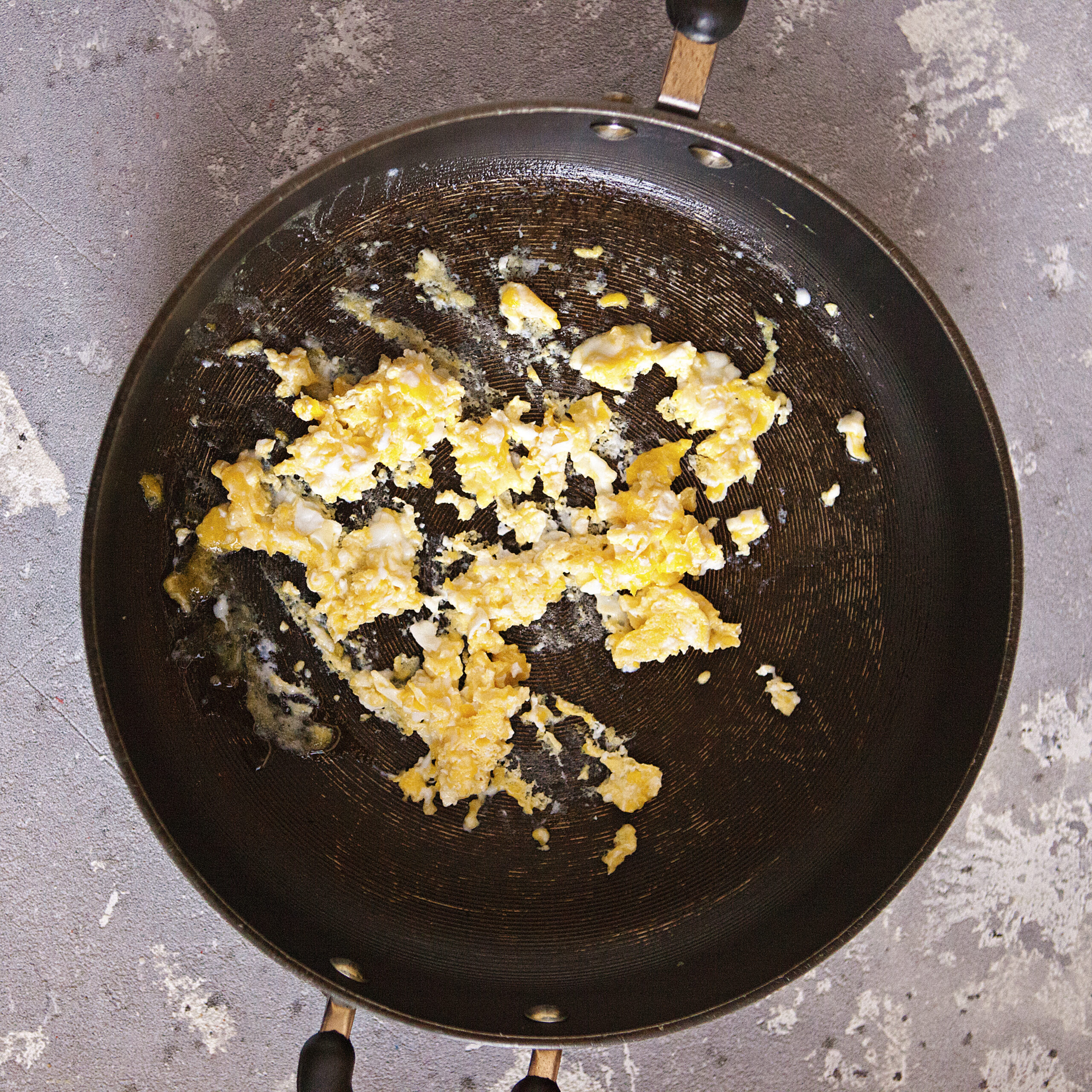 Scrambled eggs in a black skillet.