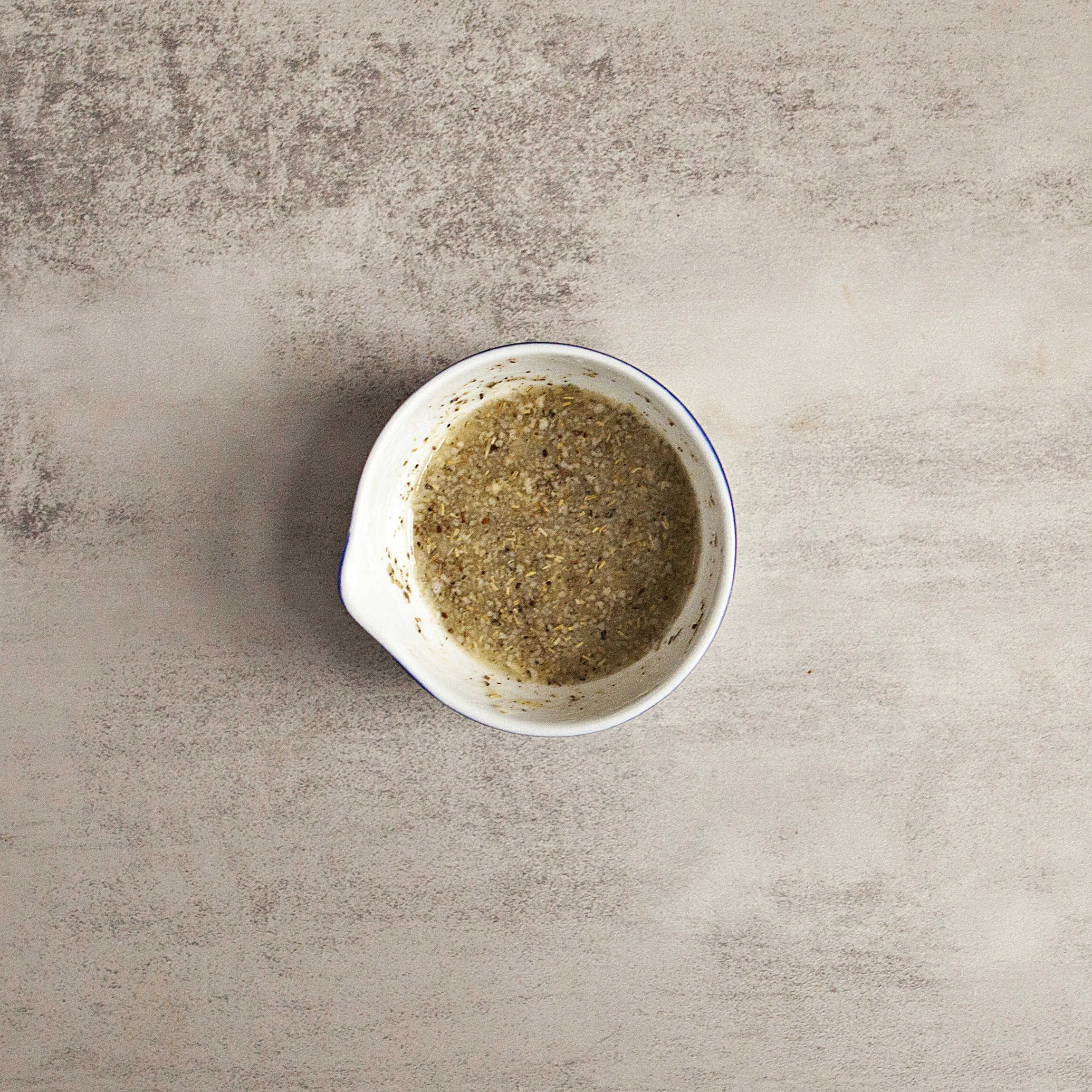 Melted butter in a ramekin with Italian seasoning and garlic powder.