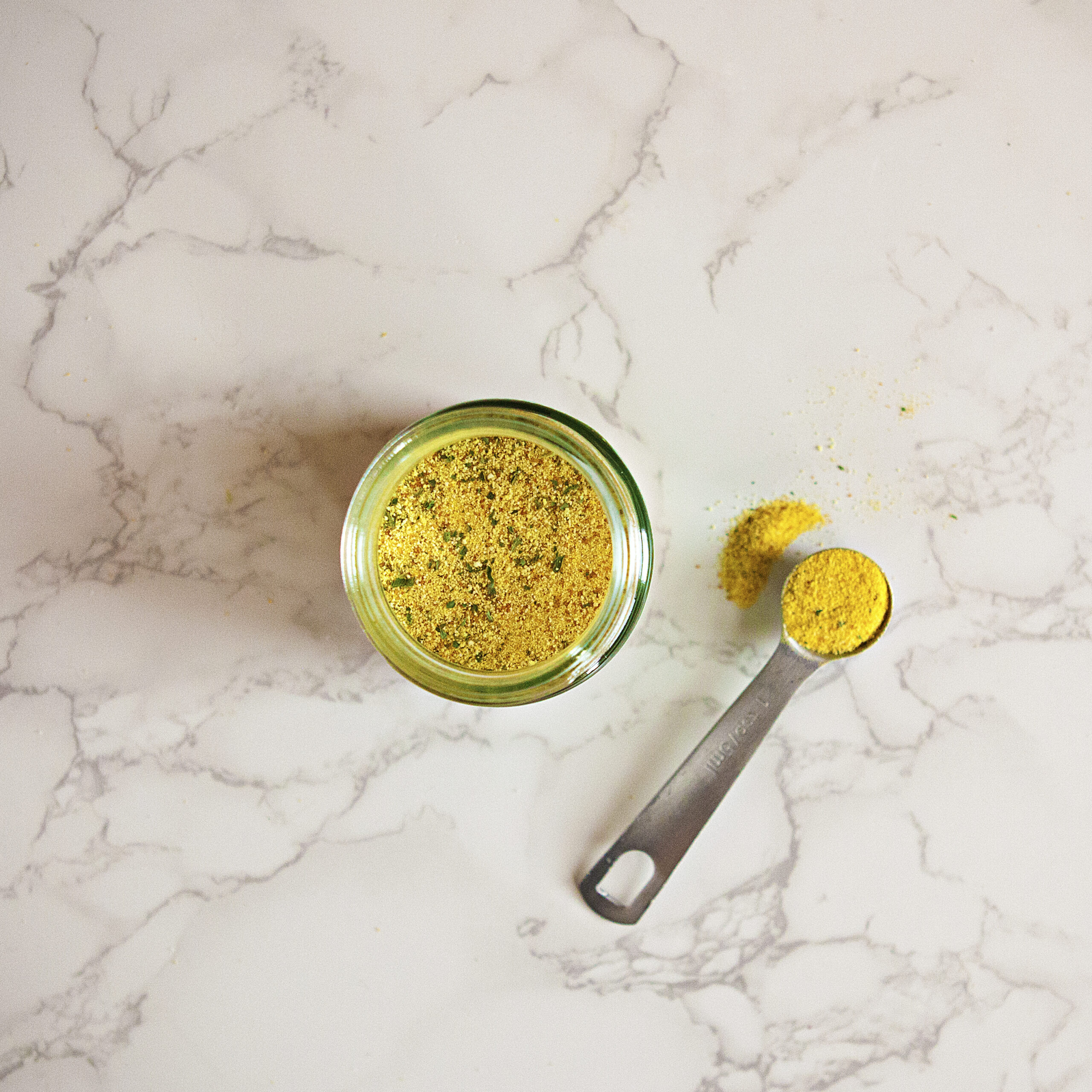 Herb Ox chicken bouillon powder in a glass bottle and a metal measuring spoon.